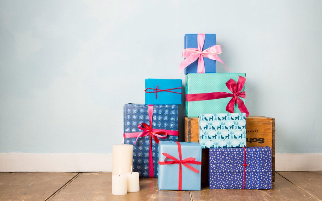 Candles and stack of wrapped christmas gifts on wooden floor